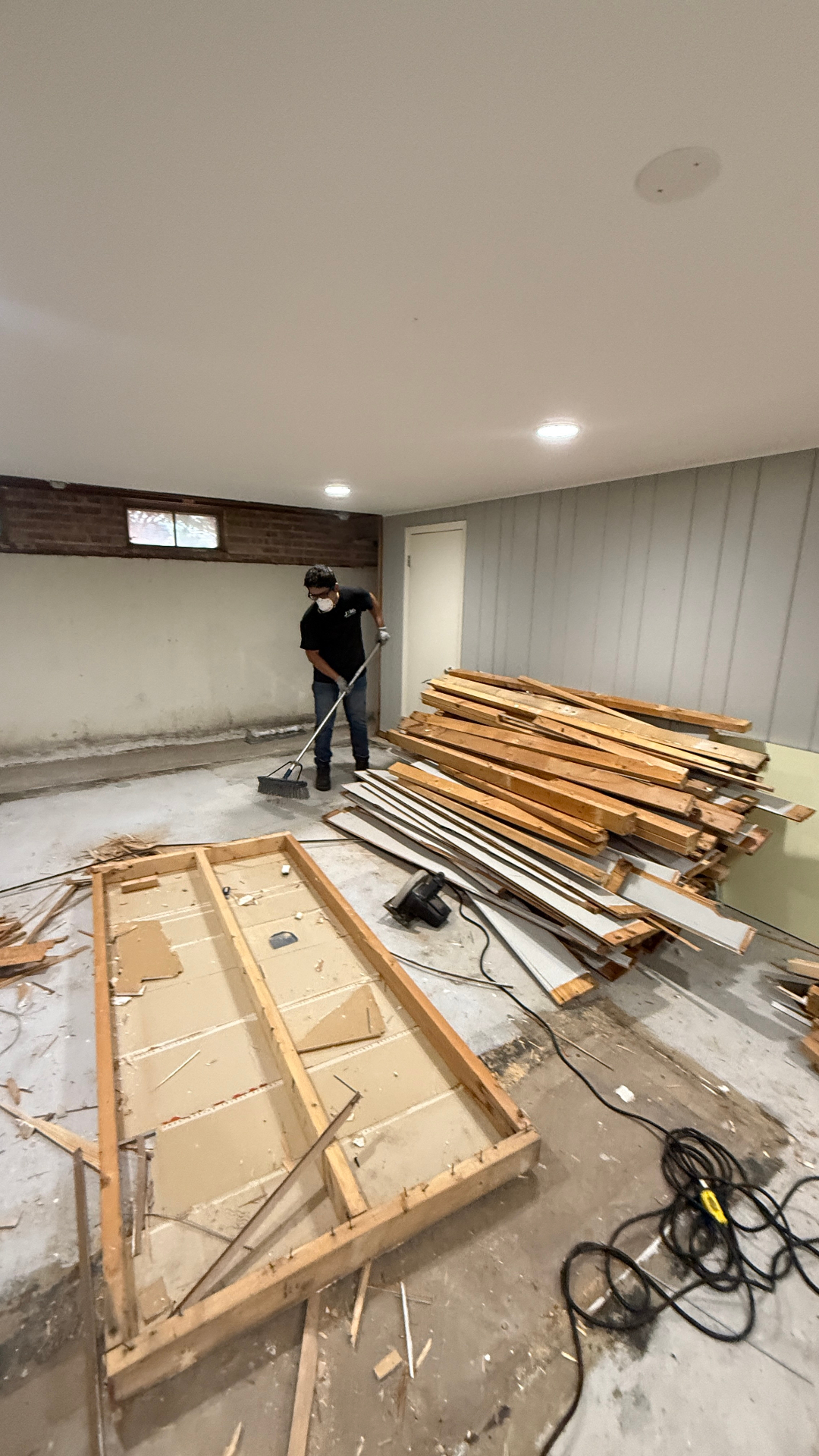 Interior demolition cleanup Arlington Heights IL — JXL crew sweeping basement after tear-out
