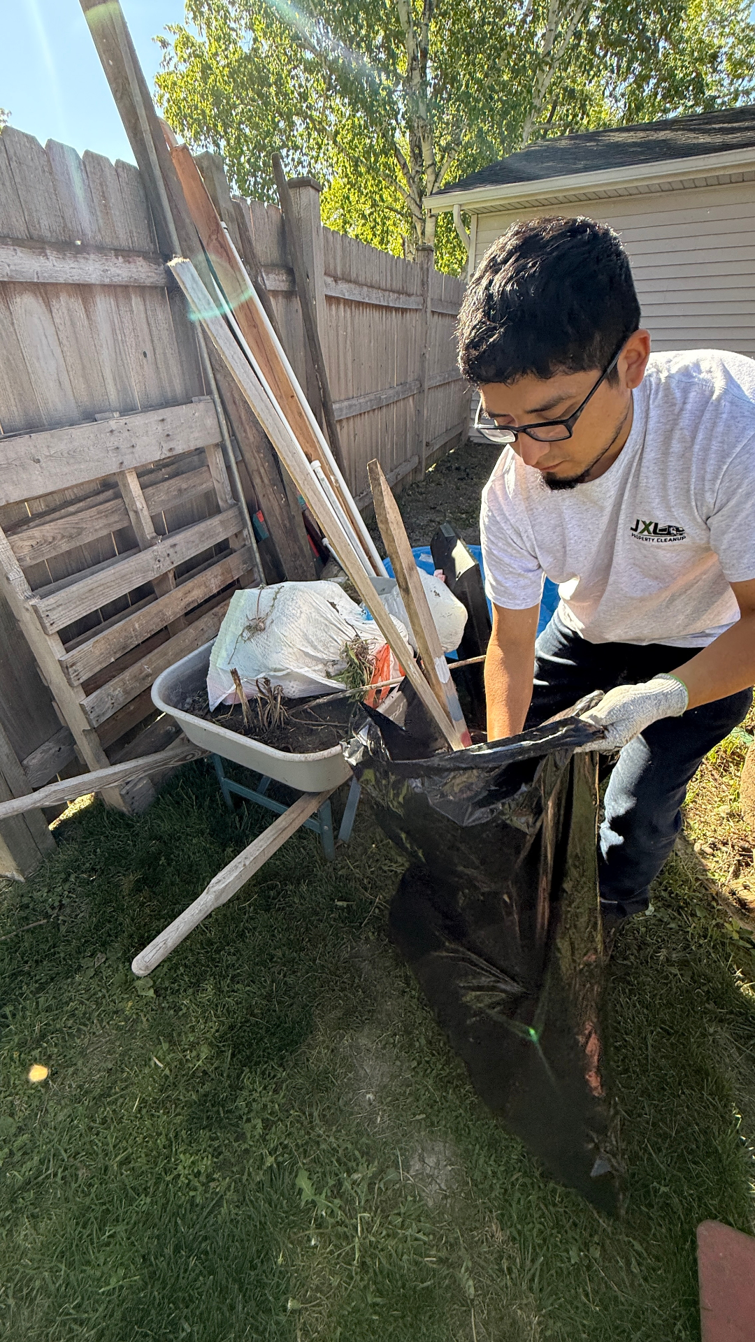 Yard cleanup Elgin IL — JXL crew bagging fence line debris