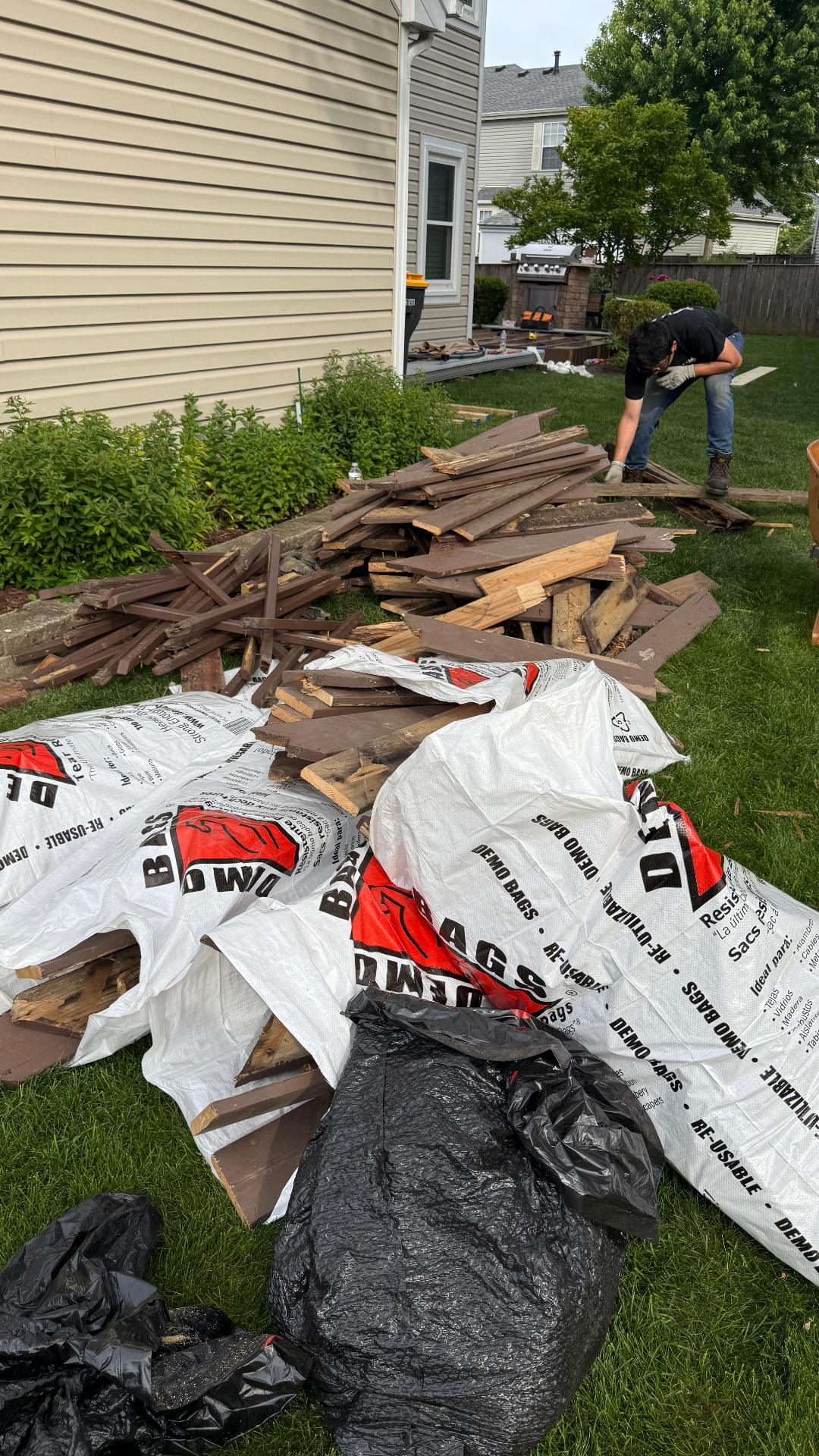 Patio demolition Streamwood IL — JXL crew tearing down old wood deck and bagging debris